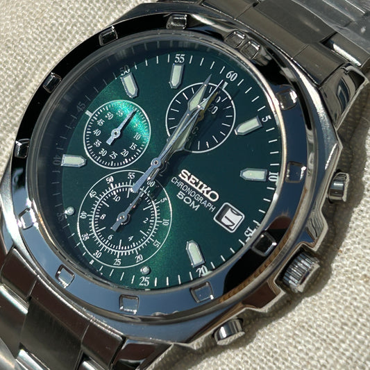 Seiko watch with green face and silver case on a textured surface